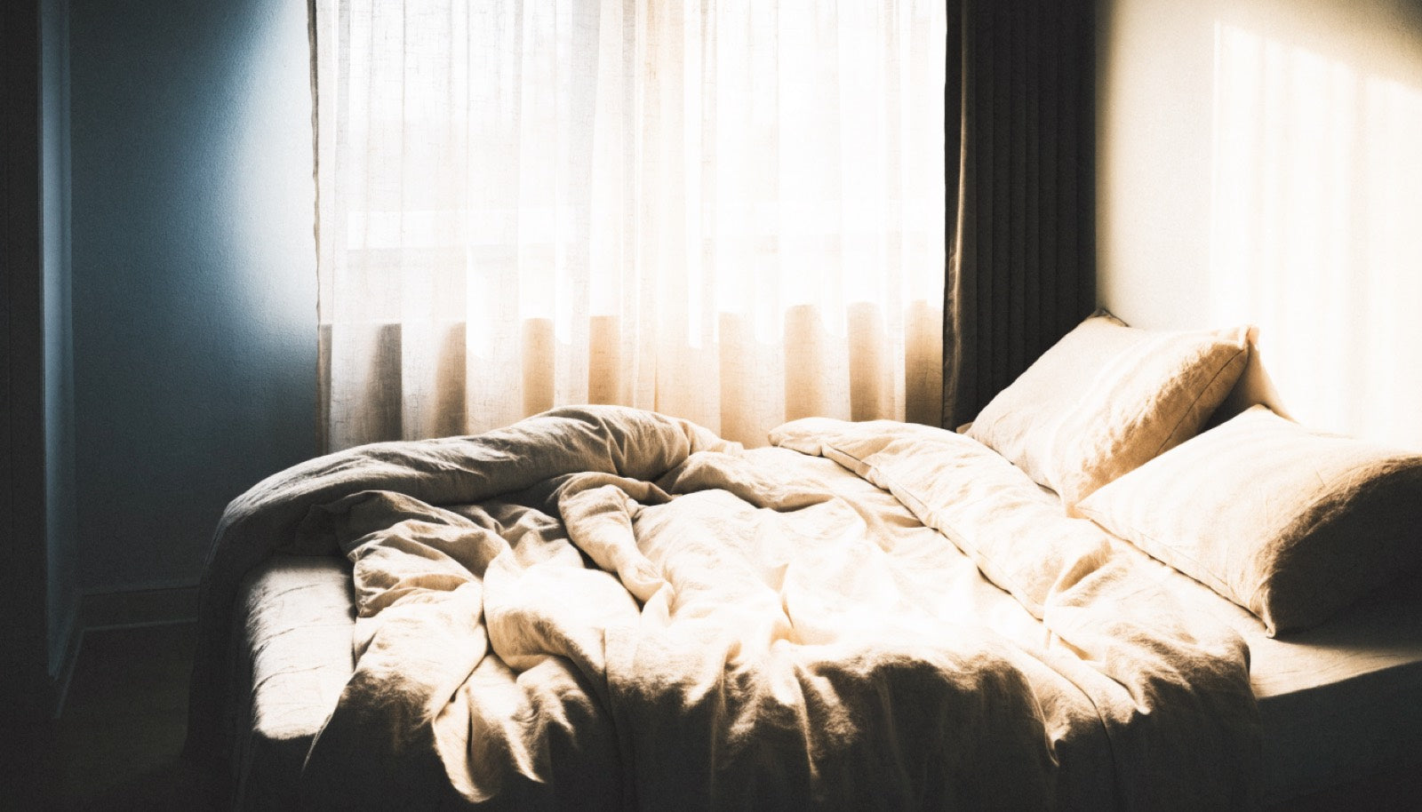Early morning light across rumpled linen bedding